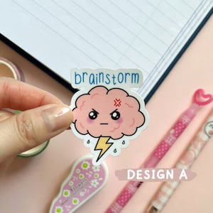 May include: A pink cartoon brain with a lightning bolt and the word "brainstorm" above it. The brain has a grumpy expression with a frown and an X for eyes. The sticker is on a pink background.