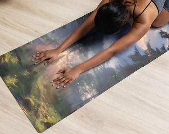 May include: A person doing yoga on a blue and green yoga mat with a forest scene printed on it. The mat has a light blue background with green trees and a sunset in the distance.