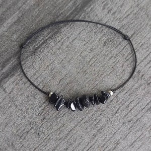 May include: A black string bracelet with black gemstone beads.