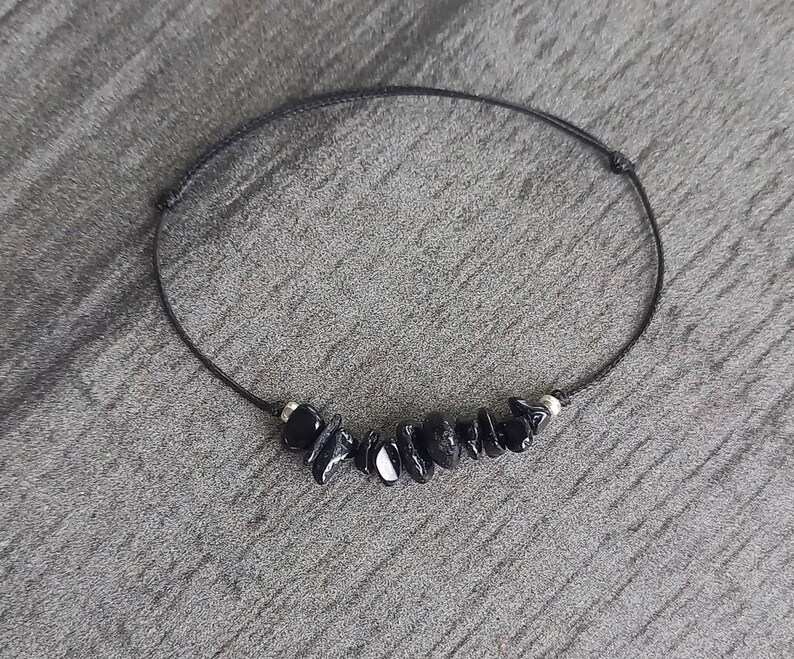 May include: A black string bracelet with black gemstone beads.