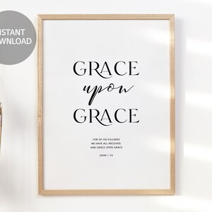 May include: A framed print with a white background and black text that reads "GRACE upon GRACE FOR OF HIS FULLNESS WE HAVE ALL RECEIVED, AND GRACE UPON GRACE JOHN 1:16".
