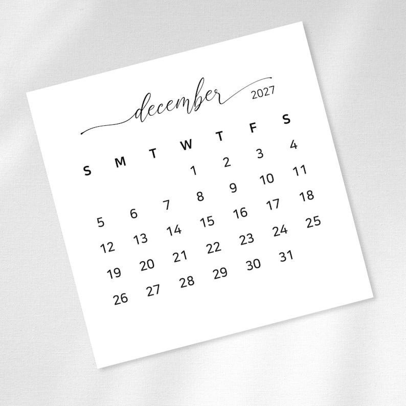 May include: A square white calendar page for December 2027 with black text. The month is written in a cursive script above the year 2027. The days of the week are abbreviated as S, M, T, W, T, F, S, followed by the numbered dates from 1 to 31.