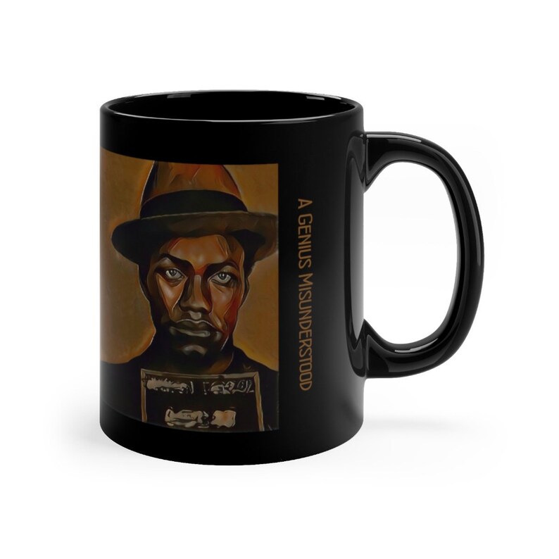 Pu&ograve; includere: Tazza in ceramica nera con un ritratto di un uomo con un cappello su uno sfondo marrone. Il testo "A GENIUS MISUNDERSTOOD" &egrave; stampato sul lato della tazza.
