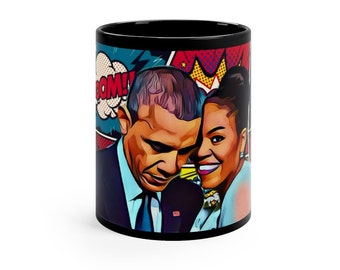 Puede incluir: Taza de café negra con un diseño de arte pop que presenta a un hombre y una mujer en un estilo de cómic colorido. El texto "BOOM!" está en un globo de diálogo.
