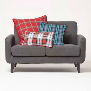 May include: A grey fabric sofa with three plaid throw cushions. The cushions are red and white, blue and white, and red and green.