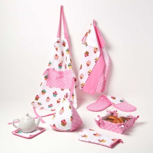 May include: A kitchen set featuring a cupcake design. The set includes an apron, oven gloves, a pot holder, a tea towel, a bread basket, and a coaster. The items have a white background with colourful cupcakes and pink polka dot details.
