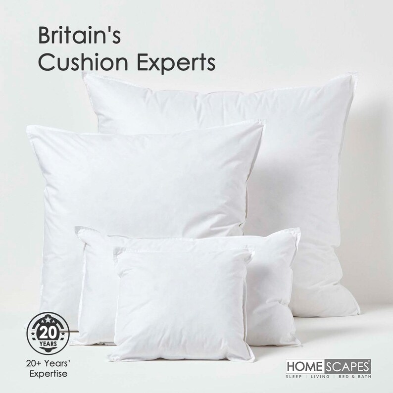 May include: A set of five white pillows of varying sizes, arranged in a pyramid shape. The pillows are made of a soft, fluffy material and have a smooth, white fabric cover. The pillows are arranged on a white background. The text "Britain's Cushion Experts" is displayed at the top of the image. A logo with the text "20 Years" is displayed at the bottom left of the image. The text "HOME SCAPES SLEEP LIVING BED & BATH" is displayed at the bottom right of the image.