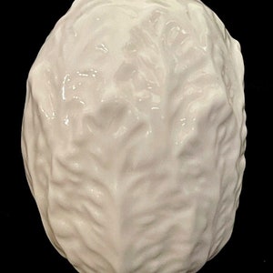 May include: A white ceramic cabbage head sculpture. The sculpture is detailed with realistic folds and textures.