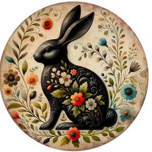 May include: A round, vintage-style decorative piece featuring a black rabbit with floral detailing. The rabbit is surrounded by colorful flowers and foliage in shades of orange, blue, and white, set against a cream-colored background.