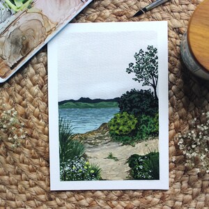 Pu&ograve; includere: Un dipinto ad acquerello di un paesaggio marittimo con una piccola isola e un sentiero che conduce all'acqua. Il dipinto &egrave; su uno sfondo bianco e ha un cielo azzurro chiaro con nuvole bianche.