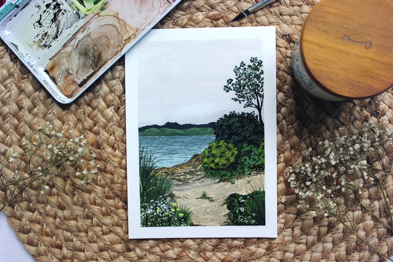 Pu&ograve; includere: Un dipinto ad acquerello di un paesaggio marittimo con una piccola isola e un sentiero che conduce all'acqua. Il dipinto &egrave; su uno sfondo bianco e ha un cielo azzurro chiaro con nuvole bianche.
