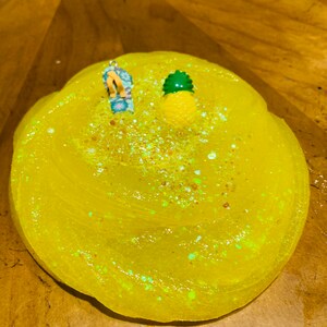 May include: Yellow slime with glitter and a small pineapple and flip-flop charm on top.