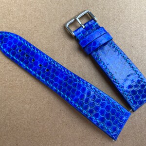 May include: A blue leather watch strap with a textured pattern. The strap is stitched with a light blue thread.