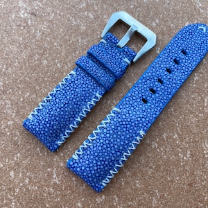 May include: A blue leather watch strap with white stitching. The strap has a stainless steel buckle.