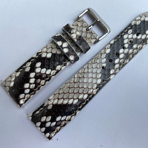 Peut inclure: Un bracelet de montre en cuir de serpent noir et blanc avec une boucle argentée.