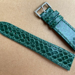 Peut inclure: Un bracelet de montre en cuir vert avec un motif texturé en peau de serpent.