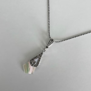 May include: A silver necklace with a teardrop-shaped pendant featuring a white mother-of-pearl stone surrounded by marcasite stones.