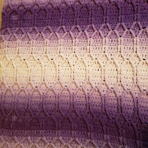 May include: A crocheted blanket with a diamond pattern in shades of purple and white.
