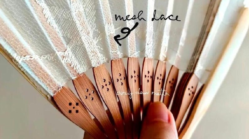 May include: A folding hand fan featuring light-colored mesh lace fabric attached to wooden ribs. The wooden ribs have a natural brown finish and are decorated with small, laser-cut floral patterns. The text mesh lace is written on the fan.