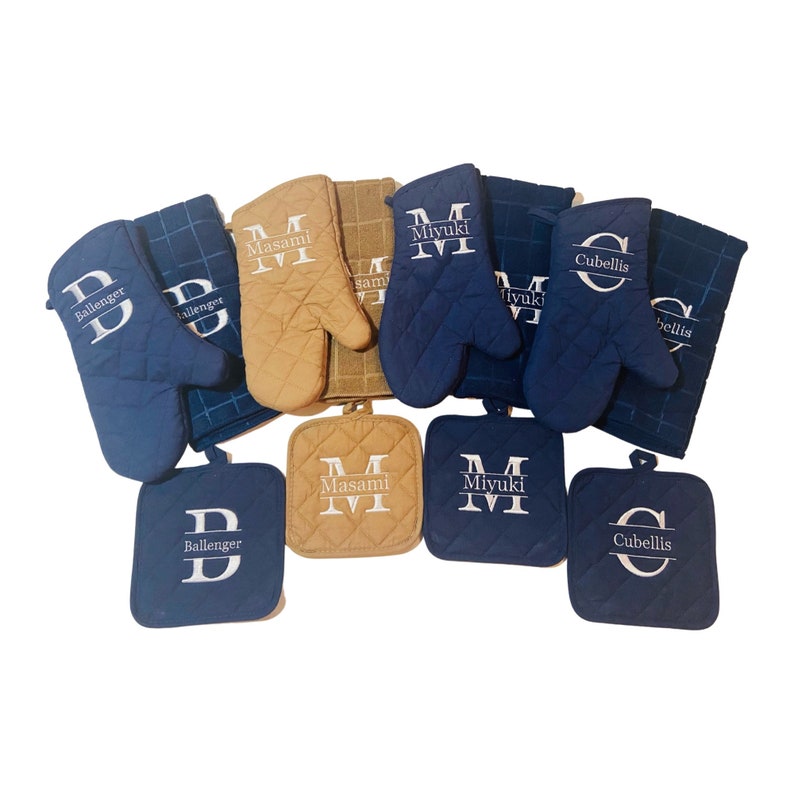 May include: Set of personalized kitchen oven mitts and pot holders. The mitts and pot holders are in blue and tan with white embroidered names. The names are Ballenger, Masami, Miyuki, and Cubellis.