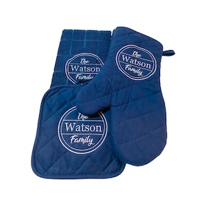 May include: A set of three navy blue kitchen accessories with white embroidery. The set includes a potholder, an oven mitt, and a dish towel. Each item features a circular design with the text "The Watson Family".
