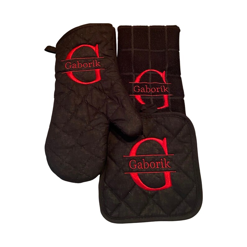 May include: A set of black quilted oven mitts and a pot holder with red embroidered lettering that says "Gaborik".