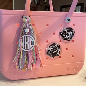 May include: Pink tote bag with a white monogram charm, a black and white "Crafers Life" charm, and a black and white "Twin Mama" charm.