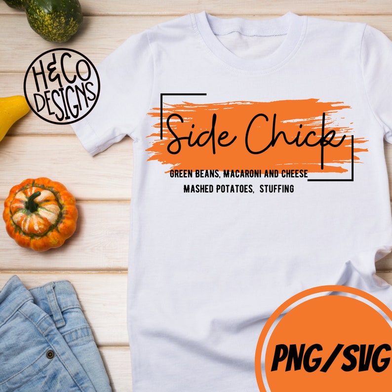 May include: White t-shirt with an orange brushstroke design and the text "Side Chick" in black. Below the design, the text reads "Green Beans, Macaroni and Cheese, Mashed Potatoes, Stuffing".
