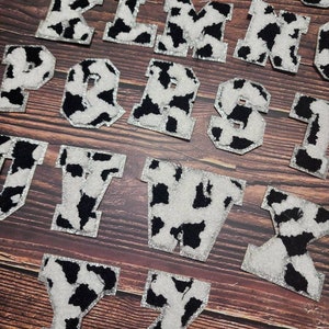 Peut inclure: Un ensemble de 26 lettres majuscules en motif vache avec une bordure argent&eacute;e scintillante. Les lettres sont faites d'un tissu duveteux et sont parfaites pour les projets d'artisanat.