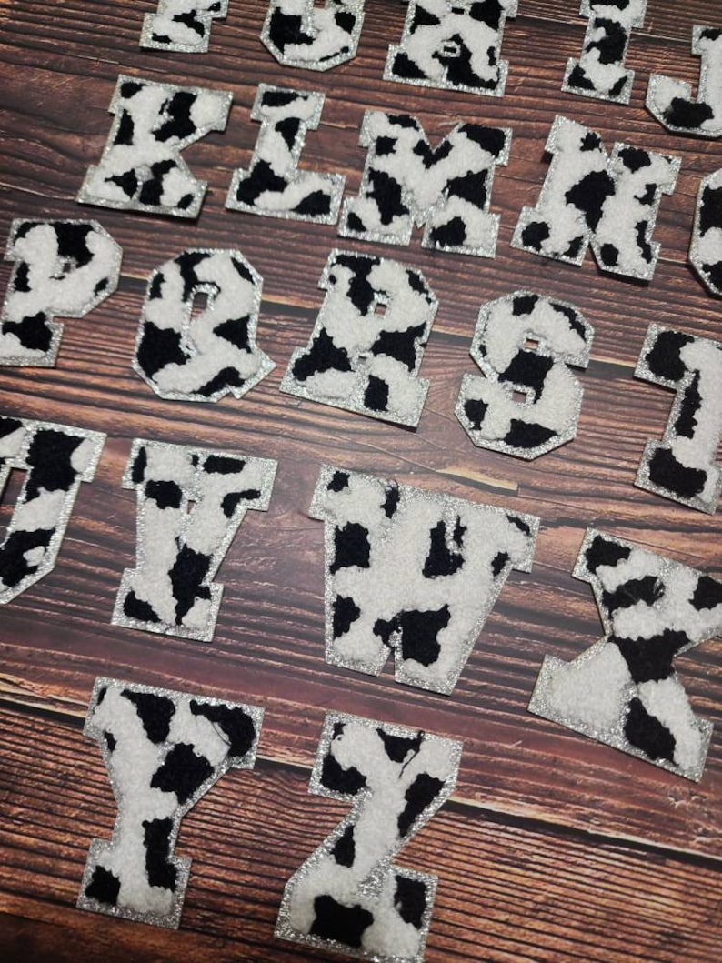 Peut inclure: Un ensemble de 26 lettres majuscules en motif vache avec une bordure argent&eacute;e scintillante. Les lettres sont faites d'un tissu duveteux et sont parfaites pour les projets d'artisanat.