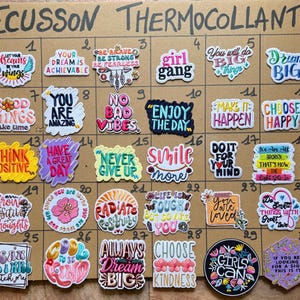 Peut inclure: Une collection de trente écussons thermocollants brodés et colorés disposés sur une grille, chacun présentant des phrases de motivation et des illustrations uniques dans des polices, couleurs et formes variées, numérotés de un à trente.