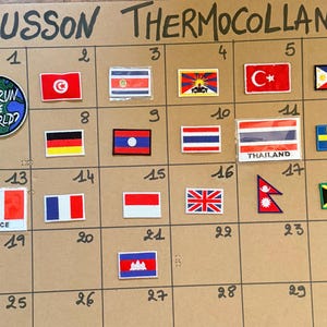 Puede incluir: Una colección de parches termoadhesivos rectangulares y circulares dispuestos en una cuadrícula numerada del 1 al 30. Los parches muestran varias banderas nacionales, incluidas Francia y Tailandia, además de un parche circular con un globo terráqueo y el texto WHO RUN THE WORLD?. El encabezado dice ECUSSON THERMOCOLLANT.
