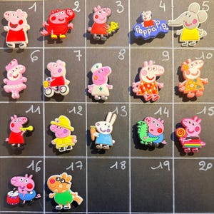 Pode incluir: Uma coleção de vinte pingentes de sapato com o tema Peppa Pig dispostos em uma grade sobre um fundo escuro. Cada pingente apresenta um personagem ou cena diferente da série, incluindo Peppa em várias roupas, uma enfermeira e um bombeiro.