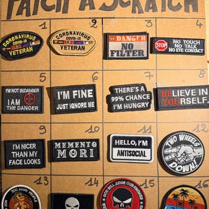 Pode incluir: Uma coleção de dezasseis emblemas bordados dispostos numa grelha com a etiqueta PATCH A SCRATCH. Os emblemas apresentam vários designs de texto, incluindo Coronavirus Veteran, Danger No Filter, I'm Fine, Memento Mori, Hello I'm Antisocial e Life's a Beach.