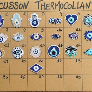 Può includere: Una collezione di ventuno toppe ricamate termoadesive disposte su una griglia con la scritta ECUSSON THERMOCOLLANT. I disegni includono mani di hamsa, occhi portafortuna, cuori e la parola LOVE in blu, bianco e turchese.