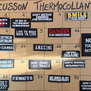 Peut inclure: Une collection d'écussons rectangulaires brodés à fond noir avec du texte blanc ou coloré, présentant diverses phrases comme "Growing old is inevitable", "Danger is my middle name" et "Not today Satan", disposés sur un panneau quadrillé.