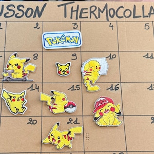 Peut inclure: Un ensemble d'écussons thermocollants brodés représentant le personnage jaune Pikachu dans diverses postures, dont sur une trottinette, avec une casquette rouge ou une Poké Ball, et un écusson rectangulaire blanc avec le logo Pokémon bleu.