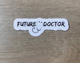 Può includere: Etichetta bianca con testo nero che recita "FUTURE DOCTOR" e un'immagine di stetoscopio in bianco e nero.