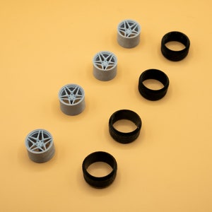 May include: A set of five gray plastic model car wheels and five black plastic model car tires.