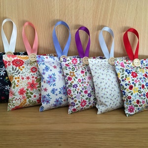 May include: Seven floral fabric sachets with different coloured ribbons and wooden buttons. The sachets are filled with dried flowers and herbs to freshen the air.