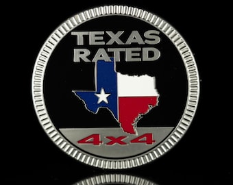 Può includere: Un emblema circolare in metallo argentato con bordo scanalato. Il centro nero presenta il testo argentato TEXAS RATED sopra un grafico della bandiera dello stato del Texas. Sotto la bandiera, il testo 4x4 è visualizzato in rosso su una barra.