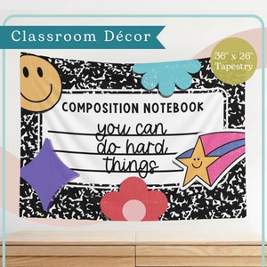 May include: A black and white composition notebook tapestry with the text "COMPOSITION NOTEBOOK you can do hard things". The tapestry is decorated with colorful stickers, including a smiley face, a flower, a star, and a diamond.