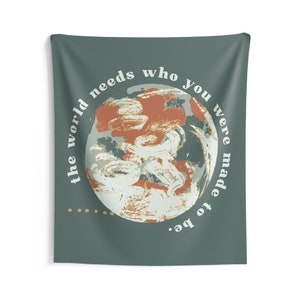 Puede incluir: Un tapiz verde azulado con un círculo blanco que contiene el texto "the world needs who you were made to be". El círculo tiene una imagen estilizada de un planeta con colores naranja, blanco y azul.
