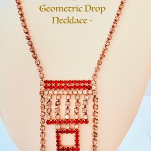 Pode incluir: Colar pendente geométrico vintage Art Deco com strass vermelhos e brancos. O colar apresenta um pendente retangular com strass vermelhos e brancos e uma corrente de pequenos strass.