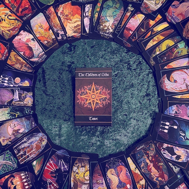 The Children of Litha tarot box, with cards displayed all around it in a circle.