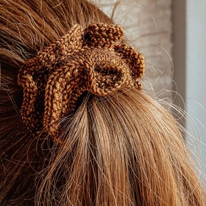 May include: A brown knitted hair scrunchie with a textured, woven design.