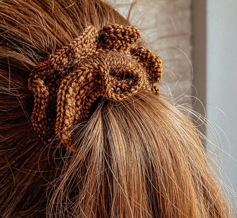 May include: A brown knitted hair scrunchie with a textured, woven design.