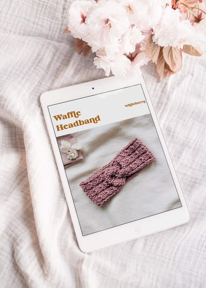 May include: A digital tablet displaying a knitting pattern for a waffle headband. The pattern is titled "Waffle Headband" and the designer is "whljberry". The headband is a dusty rose colour and is shown on a white background.