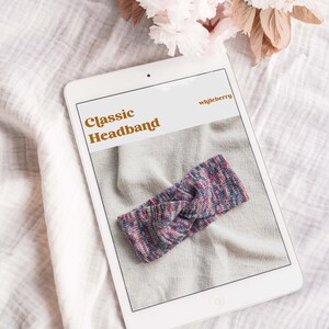 May include: A digital tablet displaying a knitting pattern for a classic headband. The pattern is titled "Classic Headband" and the designer is "whileberry". The headband is a colorful, multi-colored knit with a knot in the center.
