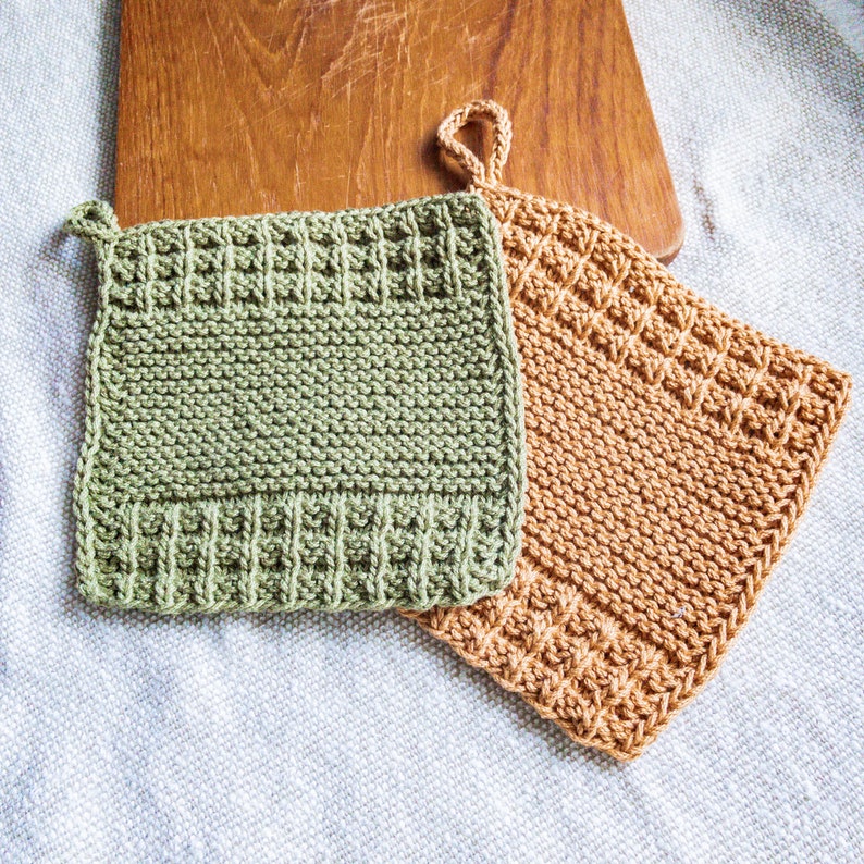 May include: Two knitted pot holders, one green and one brown, with hanging loops. The pot holders are made of a textured yarn and have a square shape.